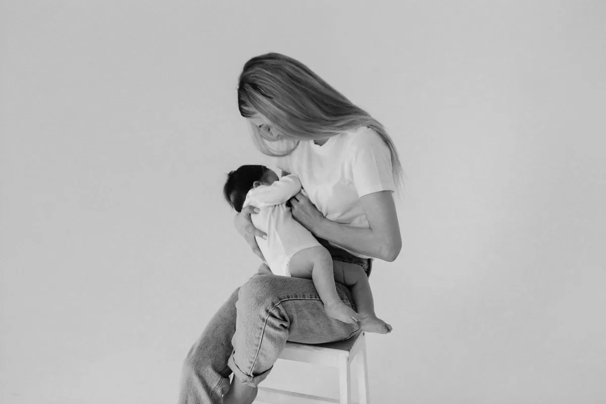 A mother breastfeeding her baby in soft black and white light