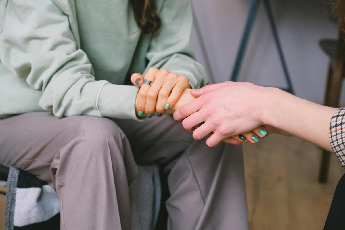 Two people holding hands in a supportive moment