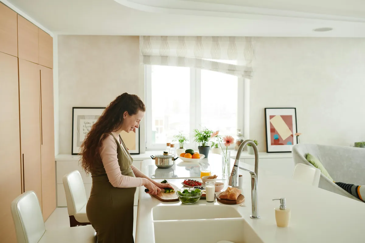 A pregnant woman preparing a healthy meal in a bright kitchen