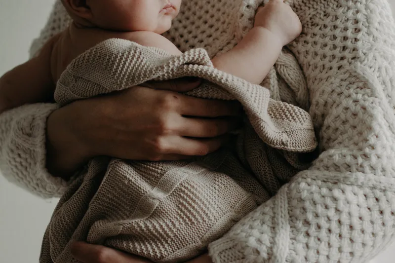 A parent holding a sleeping newborn close