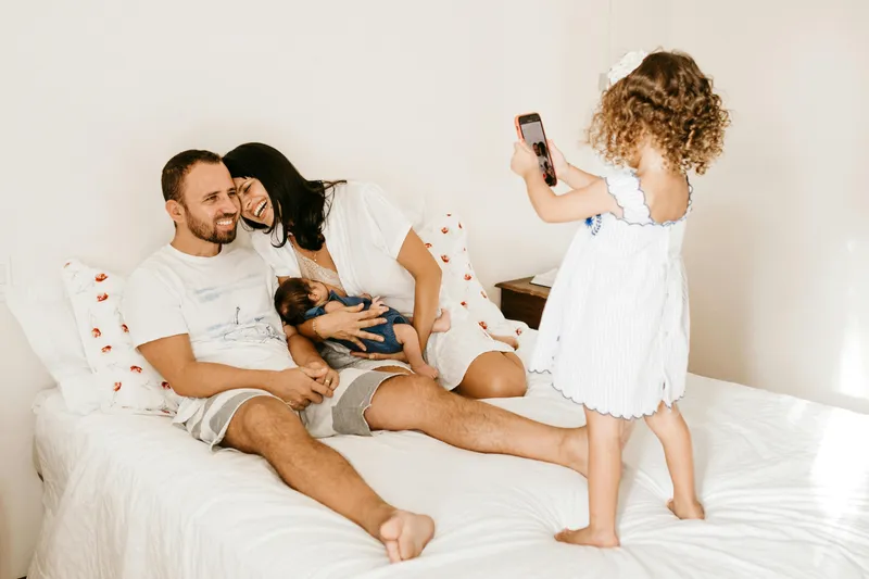 A family playing together on a bed with their toddler